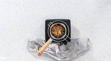 Düz yatıyordu. Çikolata parçacıkları ve diğer malzemeleri kaynayan suyun üzerinde karıştırarak çikolatalı şekerleme ve fıstık ezmesi karışımı hazırlıyorum..