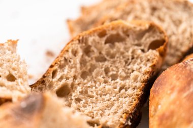 Beyaz bir kesme tahtasının üzerinde taze pişmiş ekşi ekmek dilimliyorum..