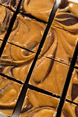 Fıstık ezmeli çikolatalı şekerlemeyi beyaz bir kesme tahtasında küçük parçalara ayırmak..