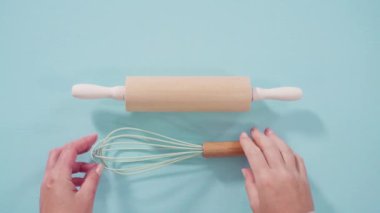 Düz yatıyordu. Mavi arka planda ahşap saplı yeni mavi silikon mutfak aletleri..