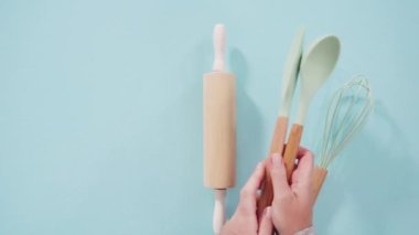 Düz yatıyordu. Mavi arka planda ahşap saplı yeni mavi silikon mutfak aletleri..