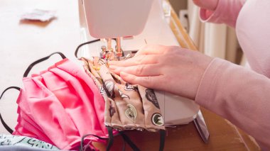 Koronavirüs salgını için dikiş makinesiyle pamuk yüz maskesi dikiyorum..