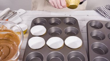 Çikolatalı ahududu kekleri pişirmek için folyolu kek bardaklarıyla kaplı kek tepsisi..