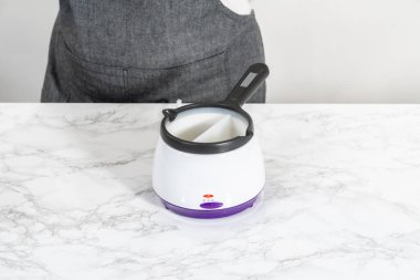 Melting chocolate chips in a candy melting pot to make red, white, and blue chocolate-covered pretzel twists.