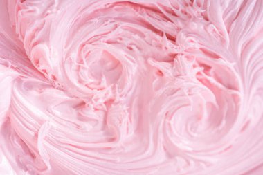 Manzarayı kapat. Vanilyalı kremanın içine pembe gıda boyası karıştırarak funfettti desenli pastayı süslemek için..