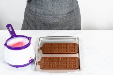 Mini pembe çikolatalar yapmak için silikon çikolata kalıbını erimiş çikolatayla dolduruyorum..