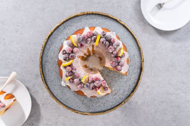 Düz yatıyordu. Dilimlenmiş limonlu kek. Şeker kızılcıkları ve limon dilimleri ile süslenmiş..