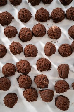 Naneli beyaz çikolatalı kurabiyeler pişirmek için parşömen kağıdıyla kaplı küçük bir hamur kepçesiyle kurabiye hamuru pişirmek..