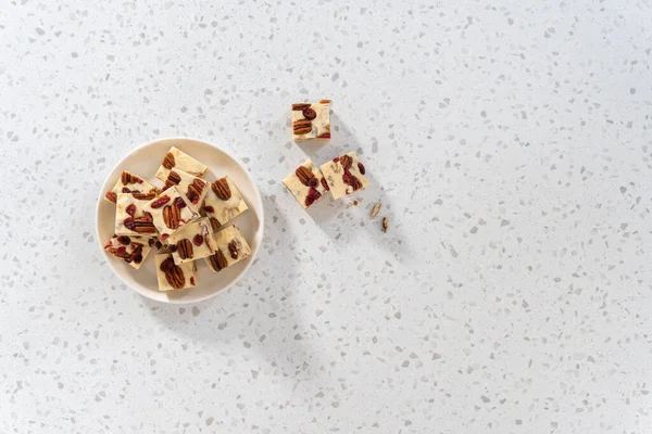 Düz yatıyordu. Beyaz seramik tabakta ev yapımı beyaz çikolatalı fındıklı şekerleme parçaları..