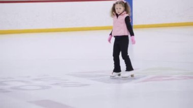 Küçük kız buz pistinde artistik patinaj yapıyor..