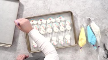 Düz yatıyordu. Adım adım. Parşömen kağıdıyla kaplanmış tek boynuzlu at şekilli bir çarşaf üzerinde krema karışımı..