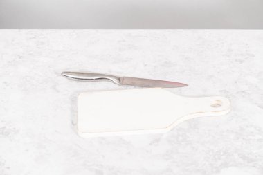 Beyaz bir kesme tahtasının üzerinde taze organik çilek dilimliyorum..