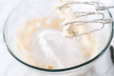 Krem peynirli krema hazırlamak için büyük bir bardakta karıştırma malzemeleri..