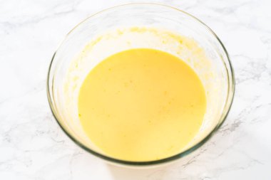 Küçük Paskalya ekmeği pişirmek için ıslak malzemeleri büyük bir bardakta karıştırıyorum..