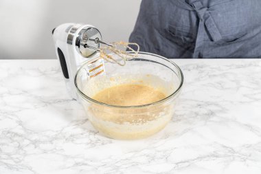 Büyük bir bardakta ıslak malzemeler karıştırarak kırmızı kadife kekler ve beyaz çikolatalı ganache kreması pişiriyorum..