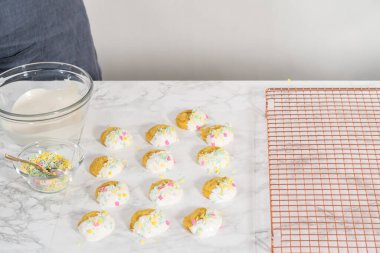 Beyaz çikolatalı limonlu kurabiye. Limonlu kurabiyeleri erimiş beyaz çikolataya batırıp Paskalya şekerleriyle süslemek..