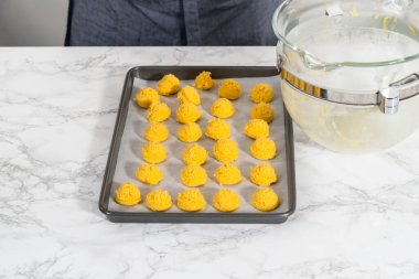 Beyaz çikolatalı limonlu kurabiye. Beyaz çikolatalı limonlu kurabiye pişirmek için parşömen kağıdıyla kaplı bir yemek tepsisine hamur kepçesiyle kurabiye pişirmek..