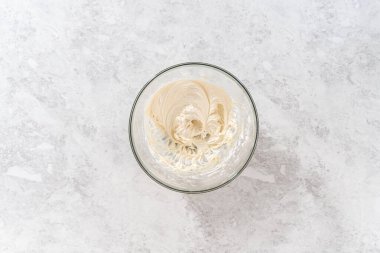 Düz yatıyordu. Havuçlu kek için krem peynirli pasta yapmak için malzemeleri büyük bir karıştırma kabında karıştırıyorum..