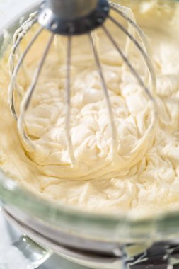 Beyaz çikolatalı ganache yapmak için mutfak mikserinde beyaz ganache çırpmak..