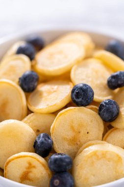 Taze yapılmış mini krep gevreği ve beyaz kasede taze yaban mersini..