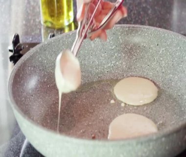 Kızartma tavasında kefir tabanında küçük krepler kızartıyorlar..