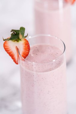 Taze taze çilek ve kağıt kamışla süslenmiş sağlıklı bir kahvaltı muzlu smoothie..