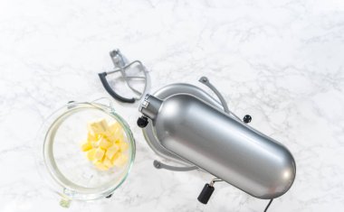 Flat lay. Whisking buttercream frosting in a glass mixing bowl with an electric kitchen mixer for American flag mini cupcakes.