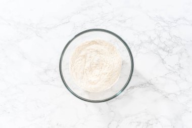 Flat lay. Mixing dry ingredients with a hand whisk in a large glass mixing bowl to bake American flag mini cupcakes.