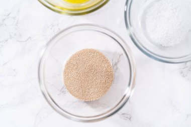 Pizza hamuru hazırlamak için cam karıştırma kabında ölçülmüş malzemeler..