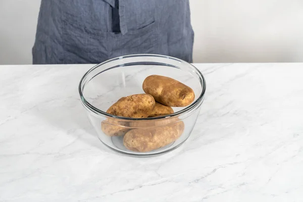Pressure Cooker Baked Potatoes. Washing raw potatoes in a glass mixing bowl with water.