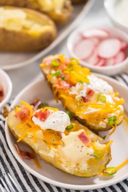 Fırında pişmiş patates. Tereyağı, ekşi krema, peynir ve pastırma parçalarıyla süslenmiş büyük fırında patates..