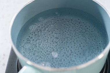 Çikolata parçacıkları ve diğer malzemeleri kaynayan suyun üzerine karıştırıp kabak aromalı şekerleme hazırlıyorum..