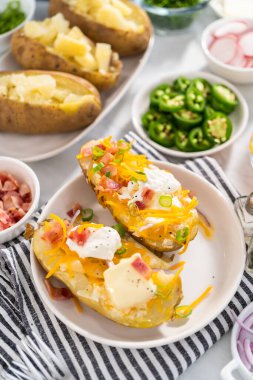 Fırında pişmiş patates. Tereyağı, ekşi krema, peynir ve pastırma parçalarıyla süslenmiş büyük fırında patates..