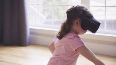 Küçük kız oturma odasında sanal gerçeklik oyunu oynuyor.,