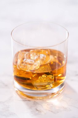 Buzlu viski, viski bardağında, beyaz mermer yüzeyde..