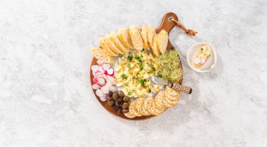 Düz yatıyordu. Sebzeli tereyağı tahtası ve tahta kesme tahtasında ekmek..