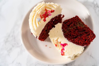 Dilimlenmiş kırmızı kadife kekler ve beyaz tabakta beyaz çikolata ganache kreması..