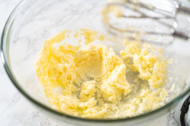 Mini vanilyalı kekler ve ombre pembe kremalı krema pişirmek için büyük bir karıştırma kabında malzemeler karıştırılıyor..