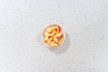 İnce dilimlenmiş kırmızı elmalar beyaz bir tabakta.