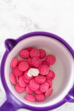 Çikolata erir, şeker tenceresinde erir. Gurme mini çikolatalar hazırlamak için çikolata serpiştirir..