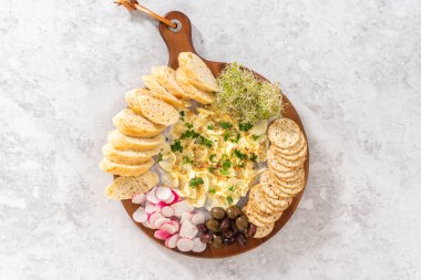 Düz yatıyordu. Sebzeli tereyağı tahtası ve tahta kesme tahtasında ekmek..