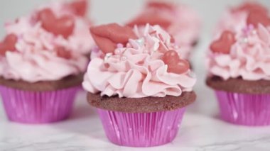 Pembe İtalyan kremalı kırmızı kadife kekler ve kalp ve öpücük şeklinde kırmızı çikolatalarla süslemeler..