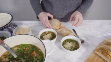 Beyaz kaselerde vejetaryen beyaz fasulye çorbası servis ediyorlar..