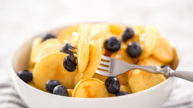 Adım adım. Taze yapılmış mini krep gevreği ve beyaz kasede taze yaban mersini..