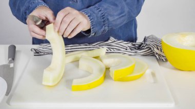 Adım adım. Beyaz kesme tahtasında kaygan altın çiğ taneli kavun.