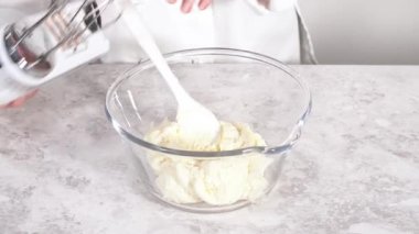 Time lapse. Mixing in pink food coloring into a vanilla buttercream frosting for decorating funfettti bundt cake.