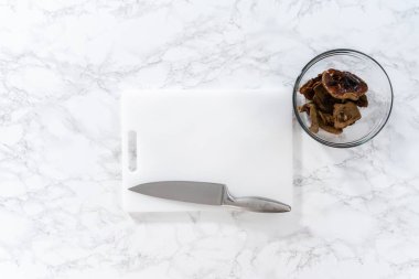 Düz yatıyordu. Beyaz kesme tahtasıyla kurutulmuş yabani mantarları doğramak..