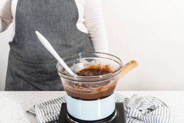 Çikolata parçacıkları ve diğer malzemeleri kaynayan suyun üzerinde karıştırarak çikolatalı şekerleme ve fıstık ezmesi karışımı hazırlıyorum..