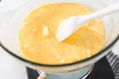 Çikolata parçacıkları ve diğer malzemeleri kaynayan suyun üzerine karıştırıp yumurta likörü hazırlıyorum..