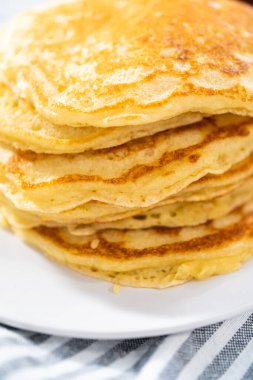 Dilimlenmiş muz, kızarmış hindistan cevizi ve akçaağaç şurubuyla süslenmiş taze hindistan cevizli krep yığını..